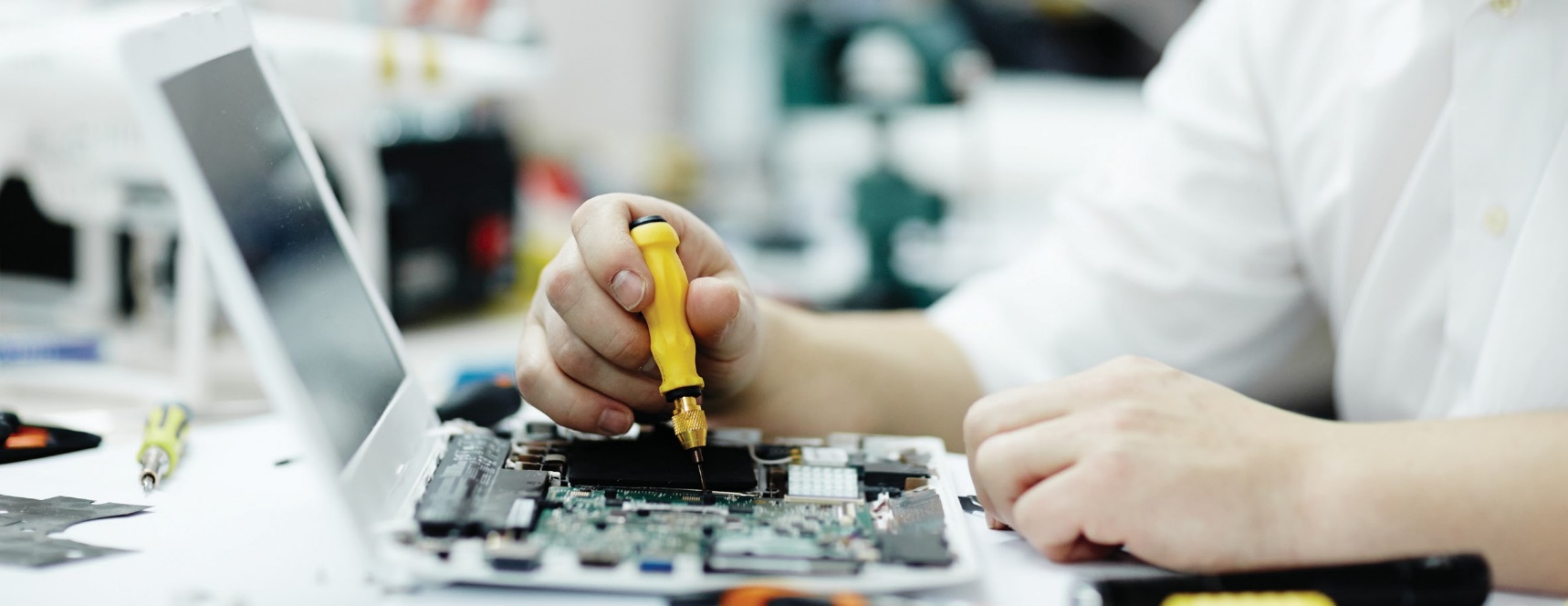 Technician repairing the motherboard of an open laptop